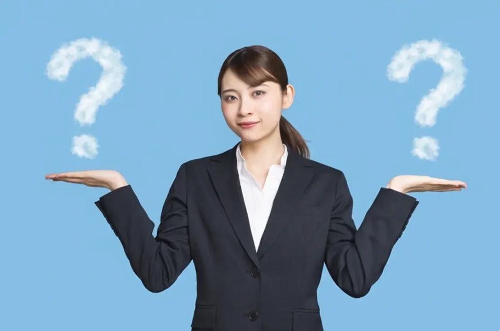 両手に浮かぶクエスチョンマークの雲を見つめる、スーツ姿の若い女性