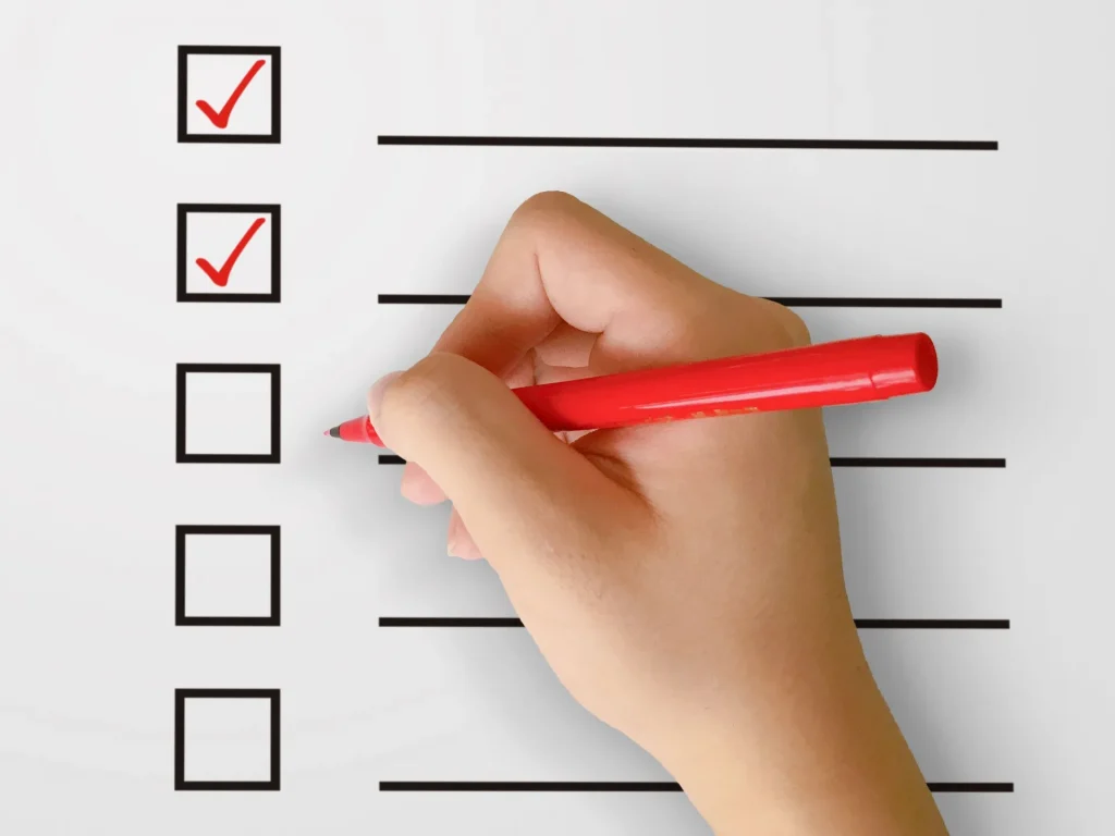 チェックリストに赤ペンでチェックを入れている手元の写真