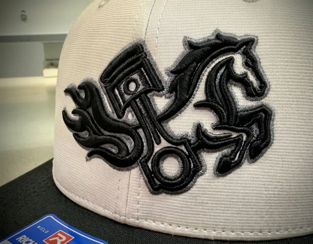 ピストンと馬のロゴが立体的に刺繍されたグレーのキャップの接写画像