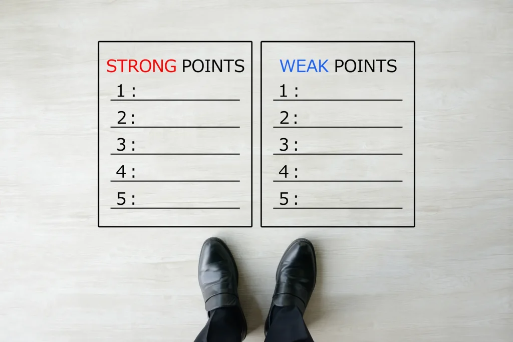 床に映し出された長所と短所のリストを見つめるビジネスパーソンの足元