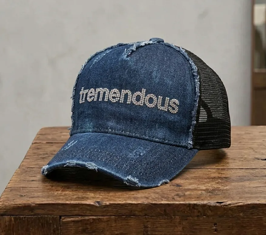 正面に「tremendous」と刺繍された、ダメージ加工のあるデニム素材のメッシュキャップ