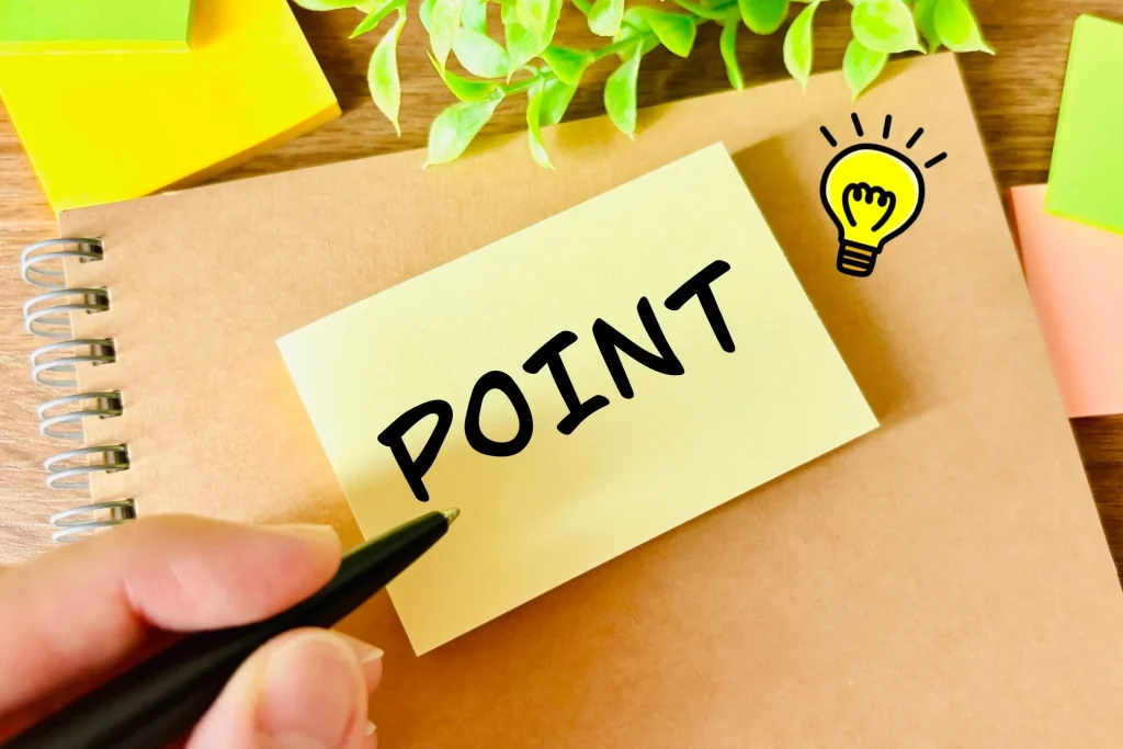 ノートの上に貼られた「POINT」と書かれた黄色い付箋と、ひらめきを象徴する電球のアイコン