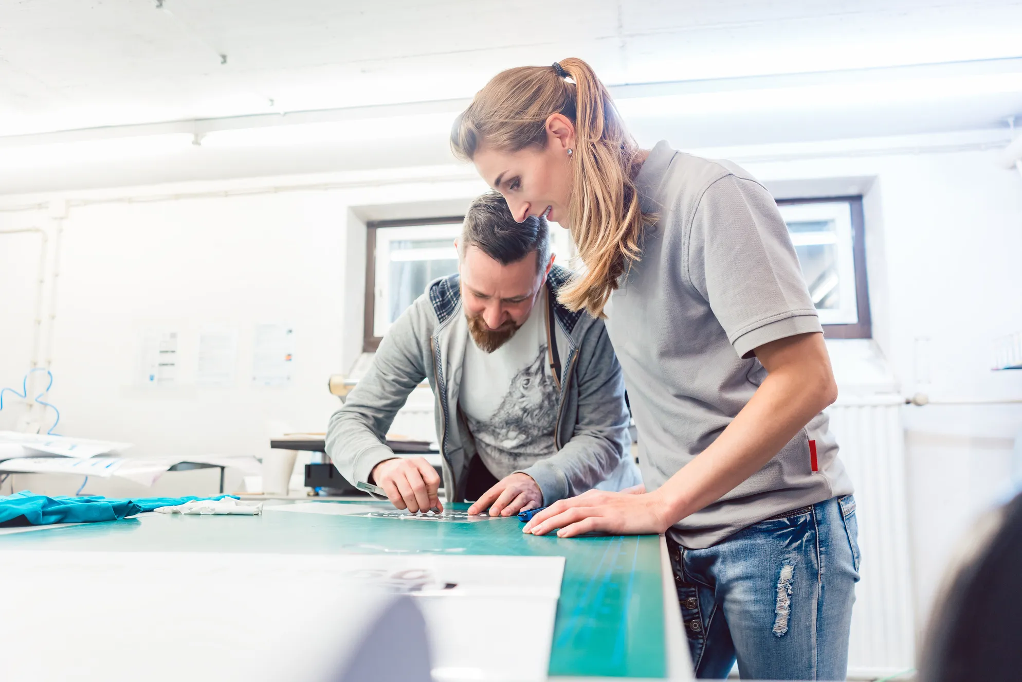 作業台でデザインの型抜きやレイアウトを確認する男女のクリエイター