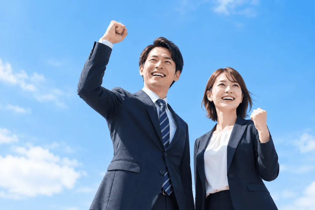 青空の下で喜ぶビジネス男女