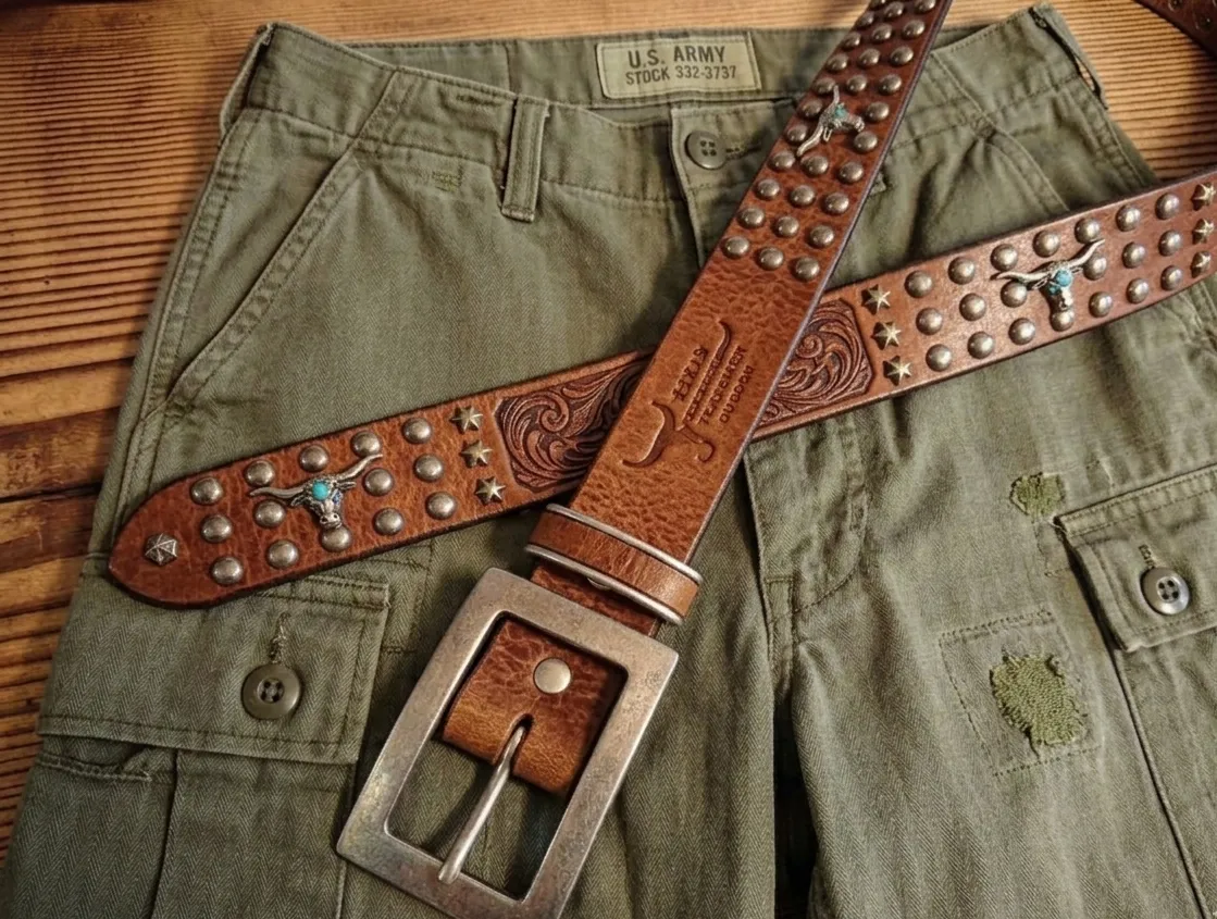 米軍のカーゴパンツの上に、スタッズや牛の頭の装飾が施された茶色のレザーベルトが置かれている様子