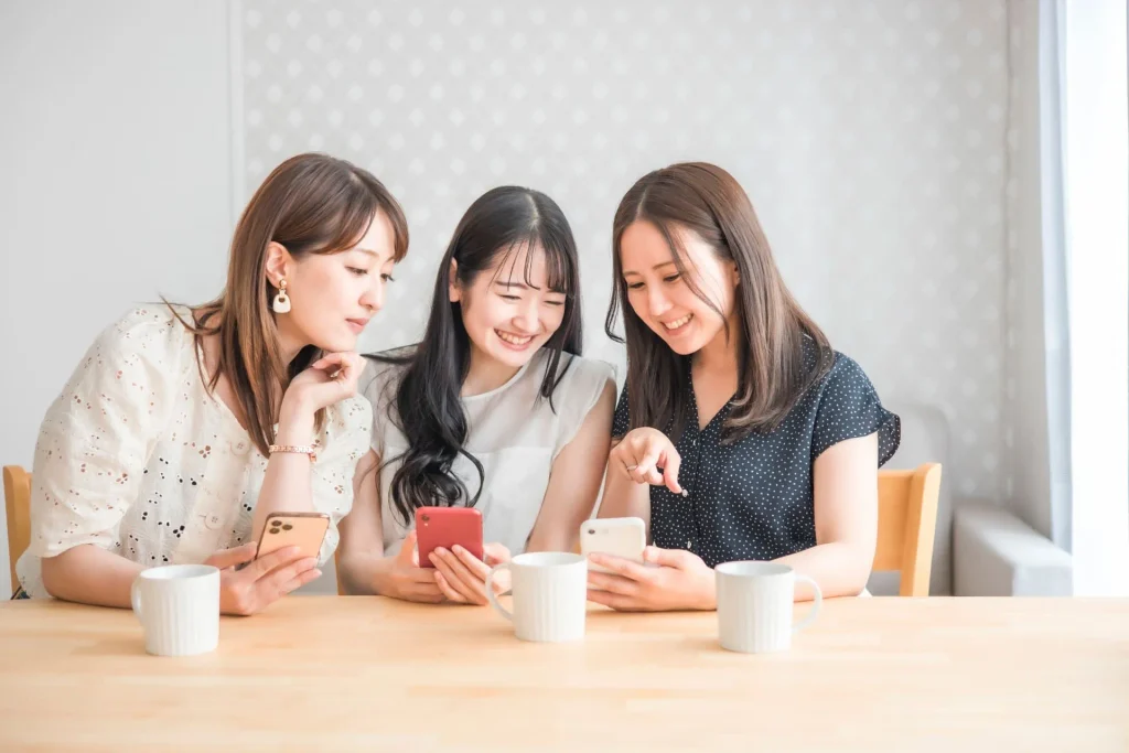 スマートフォンを見ながら会話する3人の女性