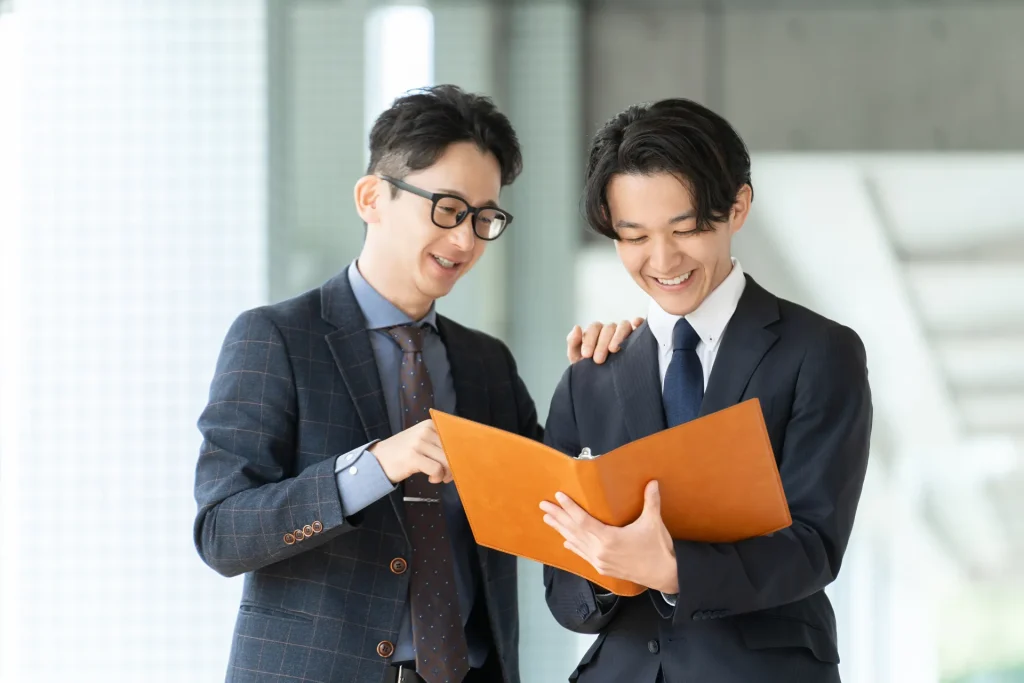 上司が部下に書類を説明しながら打ち合わせをしている様子