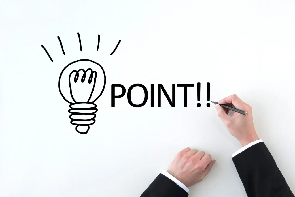 電球のイラストと「POINT!!」の文字を書き込むビジネスパーソンの手