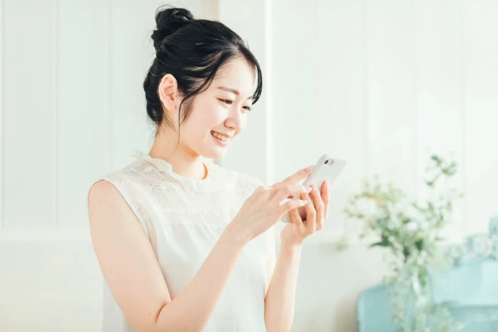 室内でスマートフォンを操作する笑顔の女性
